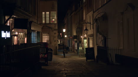 A-Man-Biking-at-Night-Through-the-Alley-in-Bath,-Somerset,-England---Wide-Shot