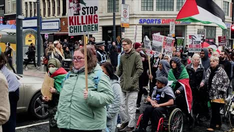 A-diverse-group-of-individuals-marches-through-the-city-centre,-carrying-signs-and-flags-in-support-of-Palestine