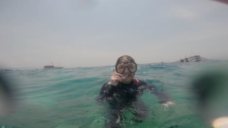 POV-footage-from-a-GoPro-captures-a-woman-floating-on-the-surface-of-the-sea,-wearing-a-diving-mask