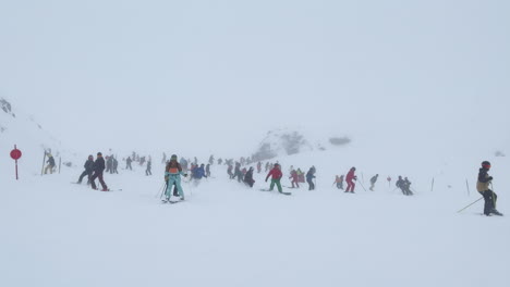 Crowded-people-trail-run-skiers-snowboarders-early-season-blizzard-white-out-skiing-snowboarding-down-mountain-slope-moguls-carve-turning-Stubai-glacier-ski-resort-Austria-Alps-October-November