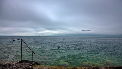 Time-lapse-water-landscape-at-Attersee-lake-Austria-stormy-clouds-motion-with-stairs-going-down-coastline