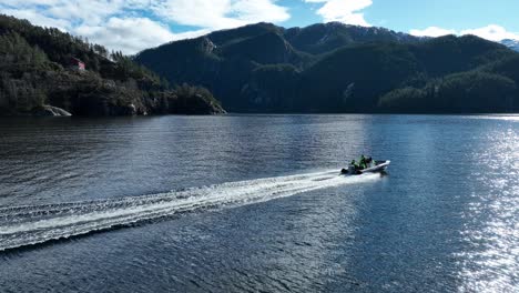 Zodiac-at-full-speed-with-tourists-during-guided-tour-in-Norway-fjord,-60-Fps-aerial