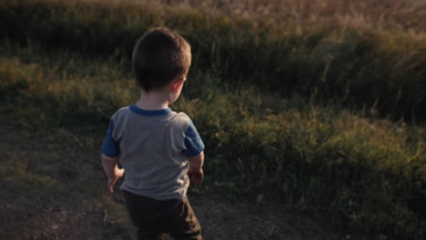 A-young,-happy-boy-playing-outside-and-throwing-dirt-in-sunset-in-cinematic-slow-motion