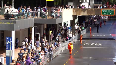 La-Gente-Se-Reúne-A-Lo-Largo-De-La-Calle-Adelaide-Con-Voluntarios-Del-Servicio-De-Emergencia-Del-Estado-De-Queensland-Que-Ayudan-Con-El-Control-De-Multitudes-En-El-Desfile-Anual-Del-Día-De-Anzac,-Garantizando-La-Seguridad-Y-El-Orden-Del-Público.