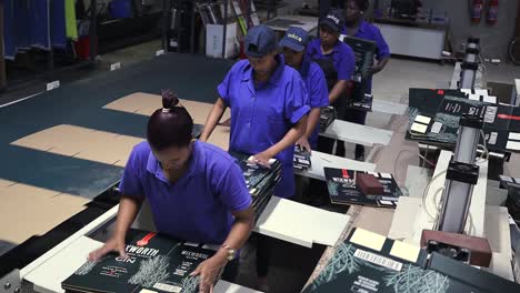 Women-in-a-production-line-removing-cardboard-boxes-from-a-conveyor-belt