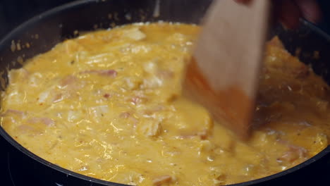 Hot-pan-of-creamy-chicken-curry-cooks-on-stove,-stirred-with-spatula