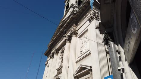 National-bank-of-Argentina-flag-waves-over-blue-skyline-basilica-catholic-church-landmark-of-buenos-aires-city-in-flores-neighborhood,-san-jose-de-flores