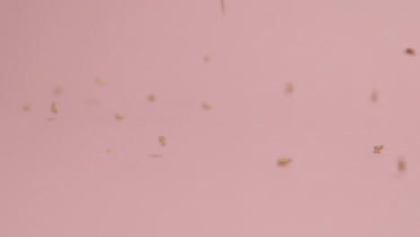 Sesame-seeds-falling-on-pink-background