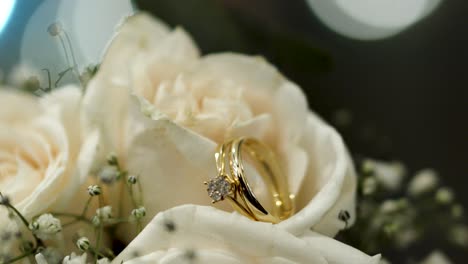 Bouquet-of-white-roses-with-shiny-wedding-rings-between-their-petals