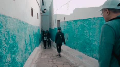 A-group-of-tourists-walking-inside-tradition-medina-of-Chefchaouen-city,-Morocco