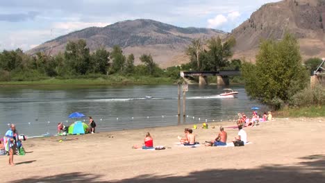 Speedboat-with-swimmers-at-river-beach,-Kamloops-BC-Canada