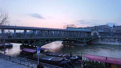 Train-passing-on-Bir-Hakeim-bridge-crossing-Seine-river,-Paris-at-sunset,-France