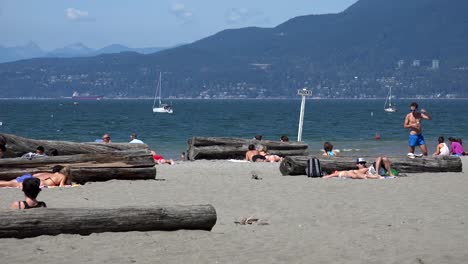 Sunbathers-on-an-ocean-beach-with-mountains-in-the-background