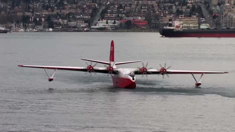 Martin-Mars-Fliegt-Mit-Einem-Wasserbomber,-Der-Auf-Der-Wasseroberfläche-Treibt