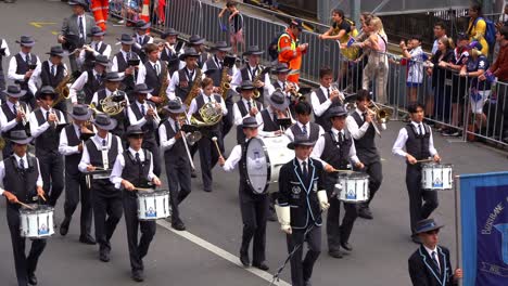 Student-musicians-from-Brisbane-Grammar-School-Band-performing-musical-instruments,-marching-down-the-street-in-Anzac-Day-parade,-paying-respect-to-those-who-served-and-sacrificed-during-the-wartime