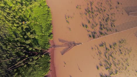 Arrow-head-fish-nets-in-muddy-waters-on-the-Tonle-Sap-shore-line,-Asias-biggest-inland-lake,-Aerial-lift-revealing-symmetrical-patterns