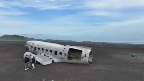 Drohnenaufnahme-Eines-Touristen-Rund-Um-Ein-Verlassenes-US-Marineschiff-DC-3-An-Der-Küste-Islands