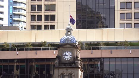 Lest-we-forget,-flying-the-Australian-national-flag-at-half-mast-on-top-of-the-clock-tower-of-Central-station-building-on-Anzac-Day,-a-sign-of-honouring-those-who-served-and-sacrificed-during-wartime