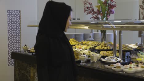 Mujer-Vestida-De-Negro-Caminando-Y-Mirando-Deliciosos-Postres-En-El-Restaurante.