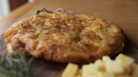 Kartoffel-Käse-Omelette,-Breite-Pfanne,-Dekoriert-Rustikalen-Holzteller-Mit-Rosmarin