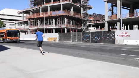 A-man-runs-in-front-of-a-construction-site-while-a-Los-Angeles-bus-passes-on-the-street