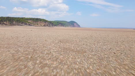 Aerial-view-of-the-beautiful-Bay-of-Fundy-during-low-tide-with-a-mountain-in-the-distance-during-a-hot-and-sunny-day-located-in-New-Brunswick,-Canada