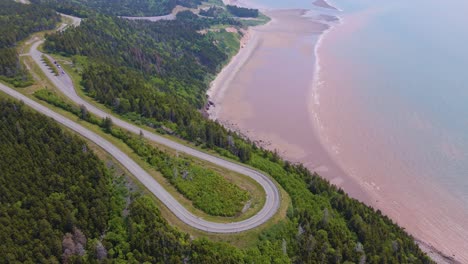 Drone-shot-panning-upwards-slowly-revealing-the-beautiful-landscape-in-New-Brunswick-of-the-famous-Bay-of-Fundy-trail-parkway-with-the-stunning-coastline-in-the-background-during-a-hot-summer-day