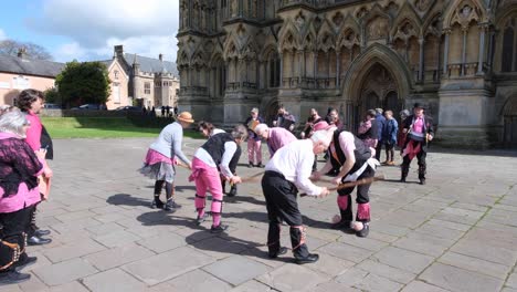 A-group-of-morris-dancers-performing-a-traditional-English-folk-dance-and-music-at-Wells-Cathedral-in-Somerset,-UK