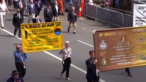 Representantes-Y-Sus-Familias-De-La-Asociación-Del-31.º-Batallón-De-Infantería-Marchando-Por-La-Calle,-Participando-En-La-Tradición-Del-Desfile-Del-Día-De-Anzac,-En-Honor-A-Quienes-Sirvieron-Y-Se-Sacrificaron.