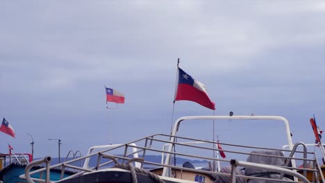 Chilenische-Flaggen-Auf-Eingelagerten-Booten-Flattern-Im-Wind-An-Der-Küste-Chiles