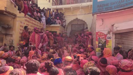 pov-shot-many-people-climbing-on-the-surrounding-building-and-Junwani-haveli-watching-the-people-playing-below-and-inside-the-gate-of-the-haveli-many-preachers-of-God-are-playing-Holi