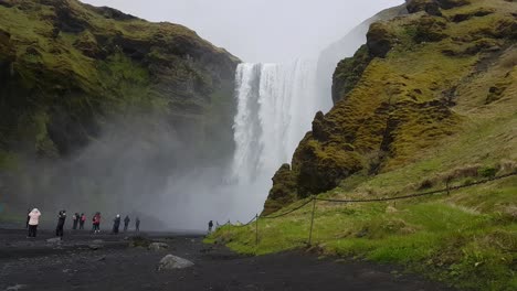 Touristen-Vor-Dem-Skogafoss-Wasserfall-An-Einem-Feuchten,-Regnerischen-Tag,-Island