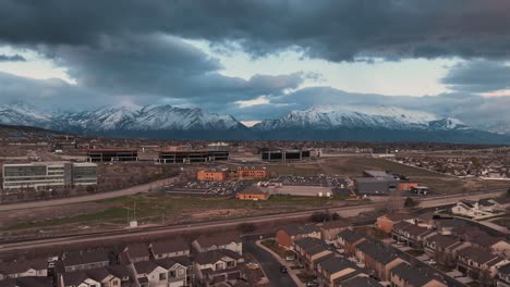 Lehi-Utah-and-silicon-slopes-beneath-snow-capped-mountains-in-spring---aerial-motion-hyper-lapse