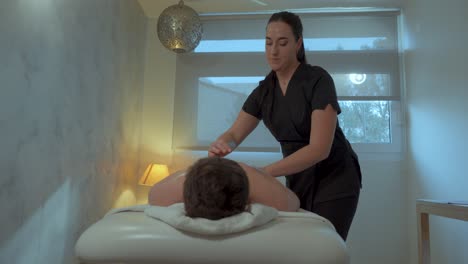 Female-masseuse-giving-back-massage-in-modern-interior-designed-salon