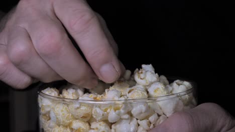 La-Mano-De-Un-Hombre-Saca-Palomitas-De-Maíz-De-Un-Cubo-De-Plástico-Y-Mira-Televisión-En-Casa