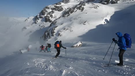 Line-of-people-practice-skiing-downhill-after-cross-country-skiing-trip,-slow-motion-handheld