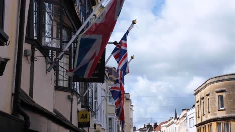 A-view-of-Union-Jack-flags-flying-on-historic-The-Crown-pub-in-Wells-Market-Place,-Southwest-of-England-UK