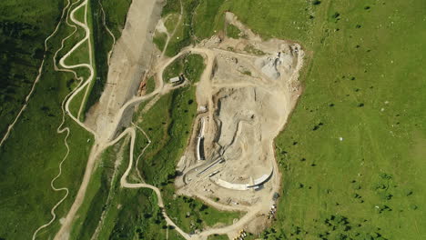 Von-Oben-Nach-Unten-Aufgenommene-Drohnenaufnahme-Einer-Staudamm-Baustelle-In-Den-Alpen