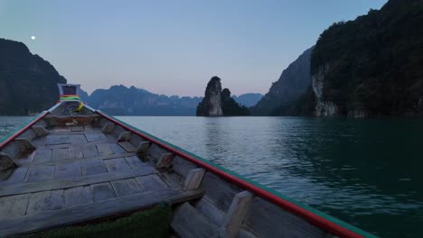 Capturing-the-tranquil-beauty-of-Khao-Sok-National-Park-in-Surat-Thani,-Thailand,-from-a-moving-tour-boat-gliding-over-the-water's-surface-during-the-evening
