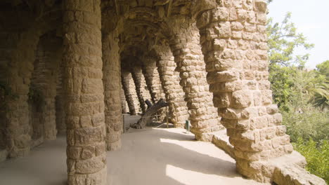 Caminando-Por-El-Parque-Güell-Bajo-Un-Camino-De-Arcadas-Y-Columnas-De-Piedra.