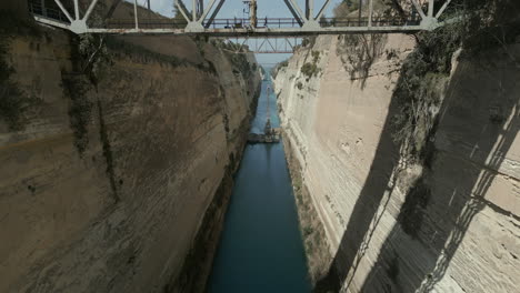 Drone-footage-in-Corinth,-Greece,-capturing-a-mesmerizing-flight-under-the-bridge-at-the-Corinth-Canal
