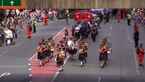 Banda-Nacional-De-Militares,-Gaiteros-Y-Tamborileros-Con-Atuendos-Tradicionales,-Tocando-Gaitas-Y-Tambores-Para-La-Ciudad-De-Brisbane-Durante-La-Tradición-Anual-Del-Desfile-Del-Día-De-Anzac.