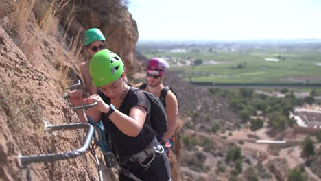 Group-of-friends-do-Via-Ferrata-climb-mountain-with-safety-equipment-in-Cartagena,-Region-of-Murcia,-Spain