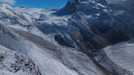 Sunny-clear-crisp-morning-Gornergrat-Zermatt-Glacier-ice-crevasse-river-Swiss-Alps-top-The-Matterhorn-summit-ski-resort-landscape-scenery-aerial-drone-autumn-Railway-Switzerland-forward-pan-reveal