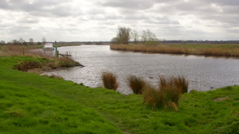 Wide-shot-of-the-river-Bure-with-a-white-board-cruiser-turning-side-on-to-camera