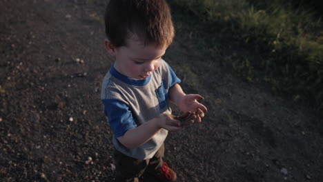 Un-Niño-Joven-Y-Feliz-Jugando-Afuera-Y-Tirando-Tierra-Al-Atardecer-En-Cámara-Lenta-Cinematográfica