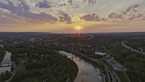 Calgary-AB-Canada-Aerial-v48-cinematic-reverse-flyover-across-Bow-river-capturing-Prince's-Island-Park,-Eau-Claire,-Chinatown-and-Downtown-cityscape-at-sunset---Shot-with-Mavic-3-Pro-Cine---July-2023