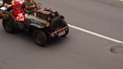 Women-ride-in-a-vintage-military-vehicle,-driving-down-the-street,-participating-in-the-Anzac-Day-parade-in-Brisbane-city,-honouring-those-who-served-and-sacrificed-during-wartime