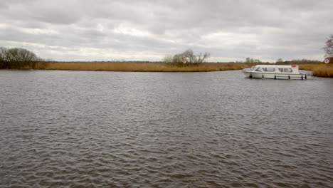 Weite-Aufnahme-Des-Flusses-Bure-Mit-Einem-Weißen-Norfolk-Broads-Cruiser-Boot,-Das-Die-Einfahrt-Zum-South-Walsham-Broad-Passiert