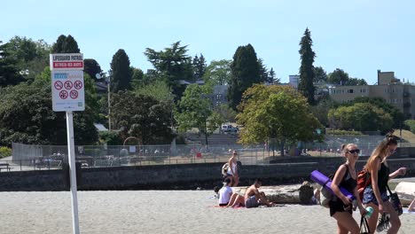 Teenage-girls-walking-on-a-beach-with-sunbathers